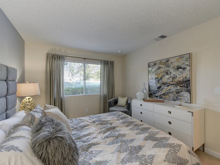 Bedroom with Mattress with Gray/White Comforter, Carpet, White Bedside Dresser with Lamp and Windows
